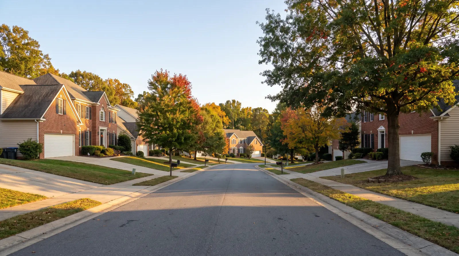Brick homes with attached garages along a tree-lined subdivision street